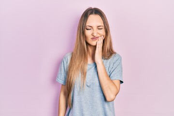 Young blonde girl wearing casual t shirt touching mouth with hand with painful expression because of toothache or dental illness on teeth. dentist