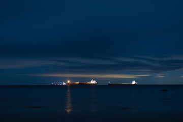 several cargo ships at night in the middle of the sea