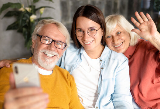 Two generation family happy elderly people with adult daughter happily take a selfie or talking to relatives via video call using a mobile phone