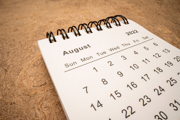 August 2022 - spiral desktop calendar against handmade paper, low angle macro shot, time and business concept