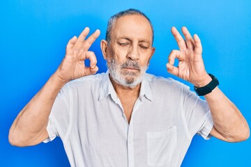 Fototapeta premium Handsome senior man with beard wearing casual white shirt relax and smiling with eyes closed doing meditation gesture with fingers. yoga concept.