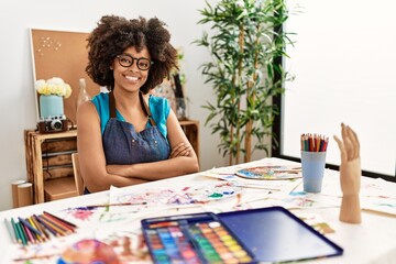 Beautiful african american woman with afro hair painting at art studio happy face smiling with crossed arms looking at the camera. positive person.