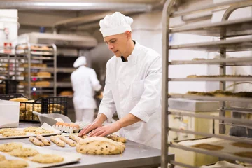Foto op Plexiglas portrait male baker making cookies in bakehouse © JackF