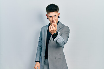 Young caucasian boy with ears dilation wearing business jacket beckoning come here gesture with hand inviting welcoming happy and smiling