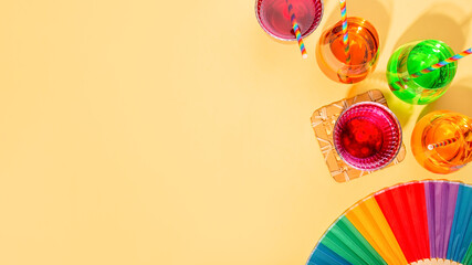 Colorful cocktails on yellow table for rainbow party with rainbow drinking straws and party...