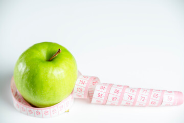 a whole green apple on a white background with a meter (measuring tape)