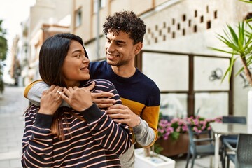 Young latin couple smiling happy and hugging at the city.