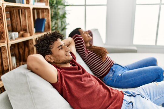 Young latin couple smiling happy relaxed with hands on head sitting on the sofa at home.