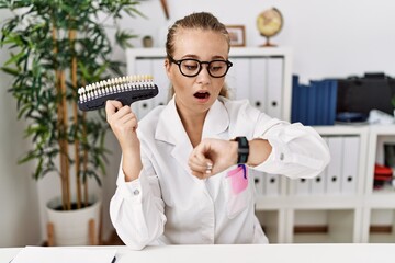 Young caucasian woman holding teeth whitening palette looking at the watch time worried, afraid of...