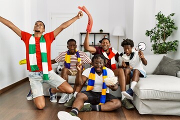 Group of young african american friends watching and supporting soccer match at home.