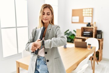 Blonde business woman at the office checking the time on wrist watch, relaxed and confident - Powered by Adobe