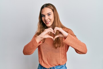 Young blonde woman wearing casual clothes smiling in love doing heart symbol shape with hands. romantic concept.