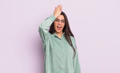 pretty young woman raising palm to forehead thinking oops, after making a stupid mistake or...