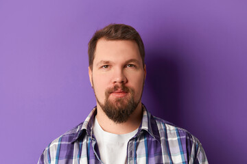 Obraz premium Happy bearded man in shirt smiling looking at camera on purple background. Young handsome stylish guy
