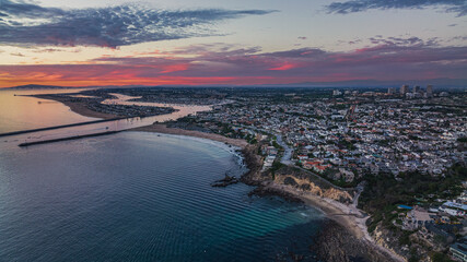 Aerial view of the ocean and a coastal California community at sunset. - obrazy, fototapety, plakaty