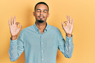 Naklejka premium Young african american man wearing casual clothes relax and smiling with eyes closed doing meditation gesture with fingers. yoga concept.