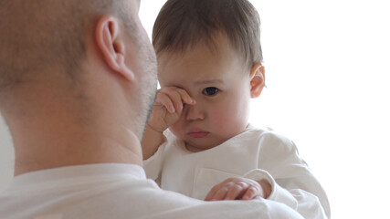 父親に抱っこされ目をこするハーフの赤ちゃん