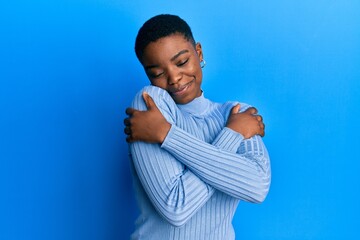 Young african american woman wearing casual clothes hugging oneself happy and positive, smiling...
