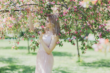 The beautiful woman in a dress in the blooming gardens.
