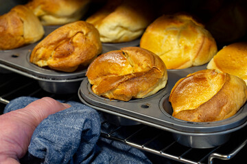 Man taking individual Yorkshire puddings out of an electric oven.  Traditional British food concept