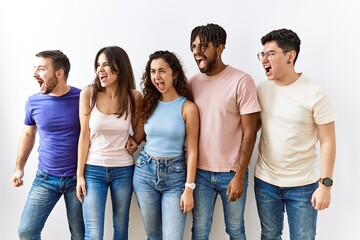 Obraz premium Group of young people standing together over isolated background angry and mad screaming frustrated and furious, shouting with anger. rage and aggressive concept.