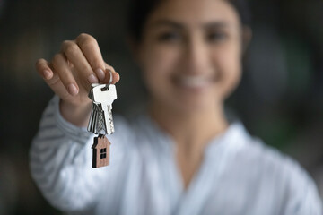 Close up focus on keys in female hands, joyful sincere young Indian ethnicity woman feeling excited of purchasing or selling own accommodation, making last mortgage payment, real estate concept.