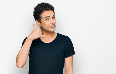 Young handsome man wearing casual black t shirt smiling doing phone gesture with hand and fingers like talking on the telephone. communicating concepts.