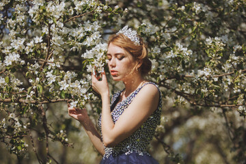 The beautiful woman in a dress in the blooming gardens.