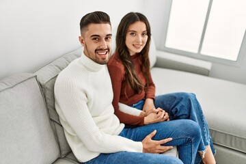 Young hispanic couple hugging and resting on the sofa and at home.