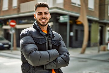 Fototapeta premium Handsome hispanic man with beard smiling happy and confident at the city wearing winter coat