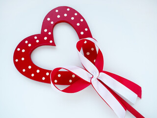 Valentine's day concept. Red wooden heart with white dots and ribbon bow on a stick. White...