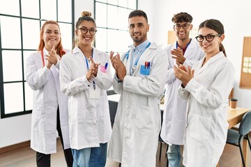 Group of young doctor smiling happy and clapping standing at the clinic office.