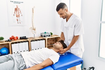 Two hispanic men physiotherapist and patient having rehab session massaging head at clinic