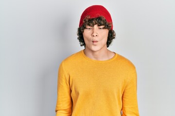 Handsome young man wearing wool hat making fish face with lips, crazy and comical gesture. funny expression.