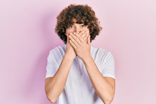Handsome young man wearing casual white t shirt shocked covering mouth with hands for mistake. secret concept.