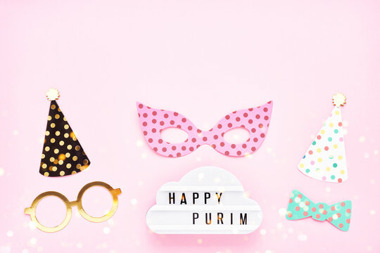 Jewish holiday Purim concept. Fun party props and lightbox with Happy Purim on a pink background