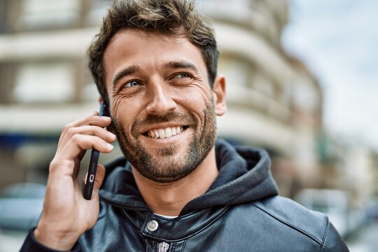 Handsome hispanic man with beard smiling happy outdoors speaking on the phone