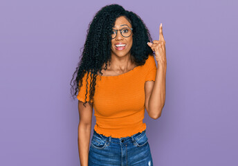 Middle age african american woman wearing casual clothes and glasses pointing finger up with successful idea. exited and happy. number one.