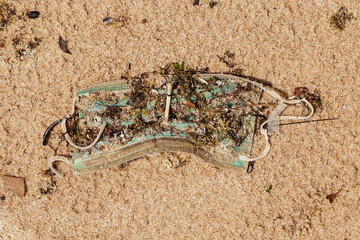 Disposable face mask discarded on the sand beach