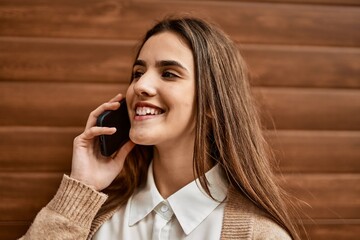 Young hispanic businesswoman smiling happy talking on the smartphone at the city.