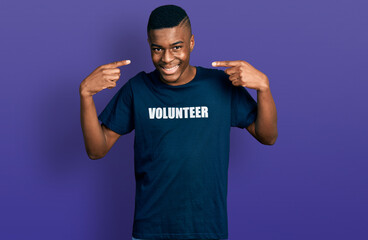 Fototapeta premium Young african american man wearing volunteer t shirt smiling cheerful showing and pointing with fingers teeth and mouth. dental health concept.