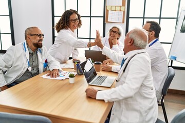 Fototapeta premium Group of middle age doctor smiling happy with hands united raised up at the clinic office.