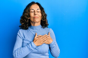 Middle age hispanic woman wearing casual clothes smiling with hands on chest with closed eyes and...