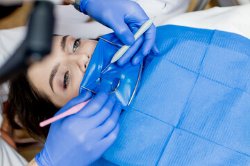 A dentist treats a woman's teeth using a cofferdam. Dental equipment