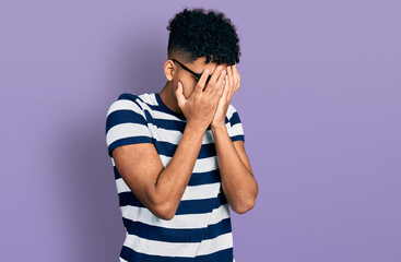 Young african american man wearing casual clothes and glasses with sad expression covering face with hands while crying. depression concept.