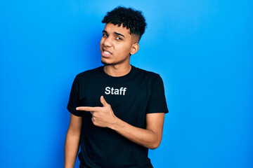 Young african american man wearing staff t shirt pointing aside worried and nervous with forefinger, concerned and surprised expression