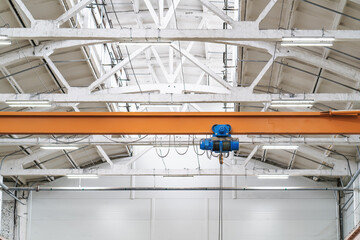 Overhead beam or bridge crane in industrial warehouse hangar building.