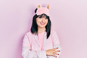 Young hispanic woman wearing sleep mask and pajama happy face smiling with crossed arms looking at the camera. positive person.