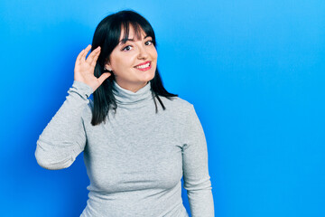 Young hispanic woman wearing casual clothes smiling with hand over ear listening an hearing to rumor or gossip. deafness concept.