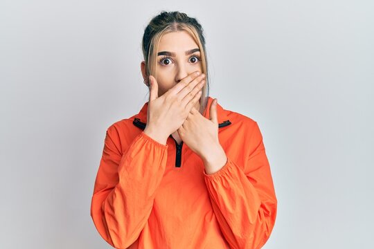 Young modern girl wearing sports sweatshirt shocked covering mouth with hands for mistake. secret concept.